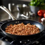 cook ground chicken in a skillet on a stovetop.